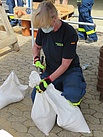 Eine THW-Helferin verschließt die Öffnung des Sandsackes, damit dieser beim Verlegen keinen Sand verliert