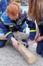 Junghelferinnen üben das Herstellen von Holzverbindungen mittels Leinen.