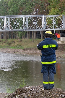 THW-Helfer kontrolliert das Einheben der fertigmontierten Behelfsbrücke.