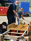 Ein THW-Helfer füllt Sand in die eigenkonstruierte Sandsackfüllapparatur