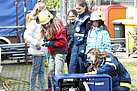 THW-Junghelferin Tatina Kremser (r.) zeigt den Teilnehmerinnen die Funktionsweise eines Stromerzeugers.